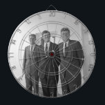 Präsident John Kennedy & Brothers American Camelot Dartscheibe<br><div class="desc">Die drei Kennedy-Brüder schlugen sich in der Sonne nieder, als sie unter dem bekannten weißen Portico des Weißen Hauses standen. Präsident John F. Kennedy, der Älteste, lehnte sich an eine Säule, ein wütendes Lächeln, das auf seinen Lippen gespielt wurde. Seine jüngeren Brüder, Robert und Ted, standen neben ihm, ihre Gesichter...</div>