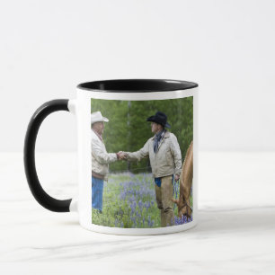 Rancher, die sich über den Zaun hinweg die Hände s Tasse