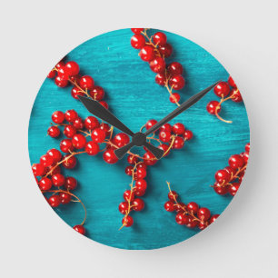 Red currant on blue background. Colorful Food Desi Runde Wanduhr
