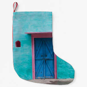 ROTE HOLZTÜR AUF BLAUE KONKRETEN WAND KLEINER WEIHNACHTSSTRUMPF