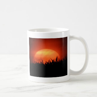 Roter Sonnenuntergang hinter schwarzem Gras Tasse