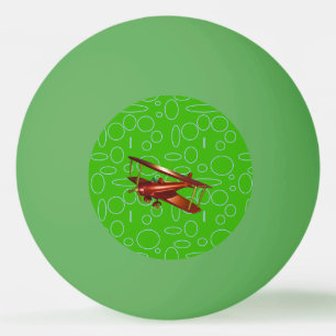 Rotes Doppeldeckerflugzeug auf grünen Kreisen und Tischtennisball