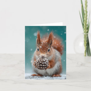 Rotes Eichhörnchen im Schnee mit Pinecone Feiertagskarte