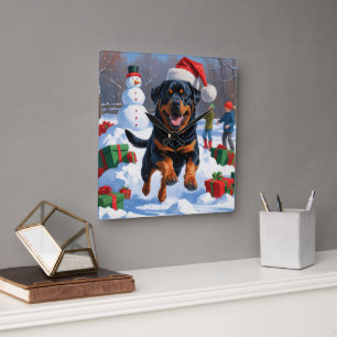 Rottweiler läuft im Schnee mit Weihnachtshut Quadratische Wanduhr