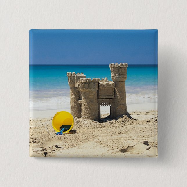 Sand-Schloss und Eimer auf tropischem Strand Button (Vorderseite)