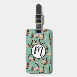 Schlechte siamesische Katzen klopfen über Gepäckanhänger