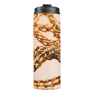 Schmale goldene Ketten auf reflektierender Oberflä Thermosbecher