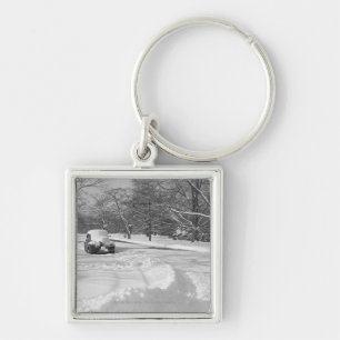 Schnee mit einer Kappe bedecktes Auto auf Straße Schlüsselanhänger