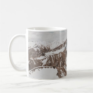 SCHNEEBEDECKTER BERG UNTER WEISSEN WOLKEN WÄHREND KAFFEETASSE