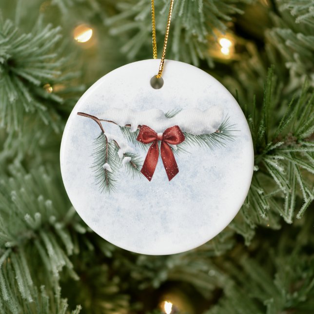 schneebedeckter Kiefernzweig mit festlichem rotem  Keramik Ornament (Baum)