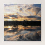 Schöne Wintersonne über dem Foto Puzzle<br><div class="desc">Dieses Puzzle bietet ein schönes Foto eines Wintersonnenuntergangs, das sich im Wasser eines Sees widerspiegelt. Der Himmel ist voll von Wolken in Pfirsich-, Blau- und Grautönen, und Sie können ein paar unbarmherzige Bäume am Horizont sehen.</div>
