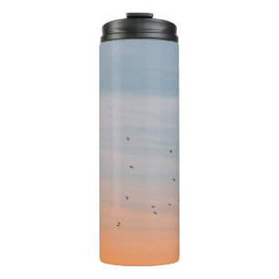 SCHWARM VÖGEL AM BLAUEN UND ORANGEN HIMMEL THERMOSBECHER