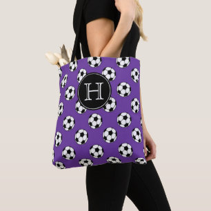 Schwarz-weiße Fußbälle auf violettem Monogramm