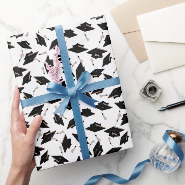 Schwarze Graduierungsklappen in der Luft auf Weiß  Geschenkpapier (Schenken)