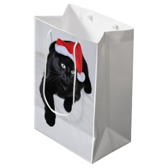 Schwarze Katze mit der roten Weihnachtsmannmütze Mittlere Geschenktüte (Vorderseite Schrägansicht)