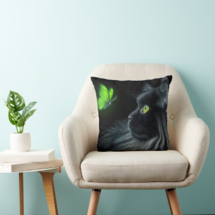 Schwarze Katze starrt auf einen leuchtend grünen S Kissen