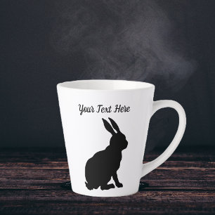 Schwarze Silhouette eines sitzenden Kaninchens im Milchtasse