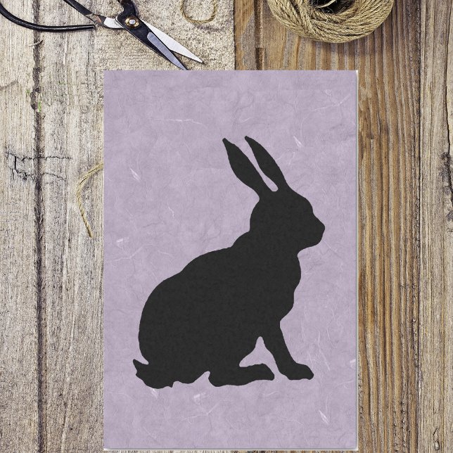 Schwarzes Kaninchen Silhouette Ostersonne Seidenpapier (Black silhouette of sitting Easter bunny on marbled pretty purple tissue paper wrapping for gift.)