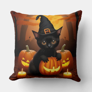 Schwarzes Kätzchen in Hexenhut zwischen Halloween- Kissen