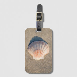 SeeMuschel, die auf Sandy-Strand legt Gepäckanhänger