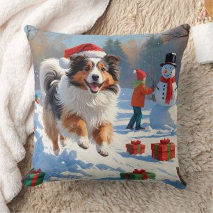 Shetland Sheepdog läuft durch Schnee mit Weihnacht Kissen