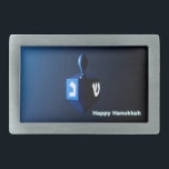 Shiny Blue Dreidel Rechteckige Gürtelschnalle<br><div class="desc">Ein modernistisches,  metallisch blaues Dreieck vor einem dunklen,  nächtlichen Hintergrund. Zwei der hebräischen Briefe,  die auf einem dreifachen gefunden wurden,  nun Nonne und glänzen,  leuchten hell. Text liest "Happy Hanukkah" auch in leuchtend blau und weiß.</div>