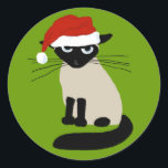 Siamese Santa Clause - Funny Christmas Cat Runder Aufkleber<br><div class="desc">Grouchy Siam Cat Holiday Stickers. Die lustige Katze trägt einen Weihnachtshut. Dieses verärgerte Kätzchen sagt Bah Humbug, einen lächerlichen Hut zu tragen. Diese lustigen Aufkleber eignen sich perfekt, um die Rückseite der Urlaubshüllungen zu schließen. Besuchen Sie Jenn’s Doodle World für lustigere Katzenfreunde-Produkte und coole Geschenke mit diesem humorvollen Xmas Cat...</div>