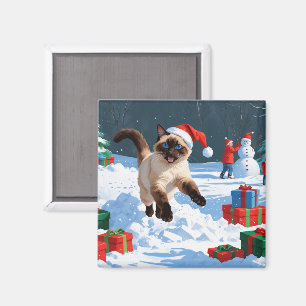 Siamische Katze läuft im Schnee mit Weihnachtsmütz Magnet