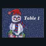 Smiling Snowman Holding String of Christmas Lights Tischnummer<br><div class="desc">This table number card for your parties or events has a smiling snowman with a carrot nose wearing a winter blue and red hat and scarf holding a lit string of colorful Christmas lights on a dark blue background with falling snow.  Customize your table number with the template.</div>
