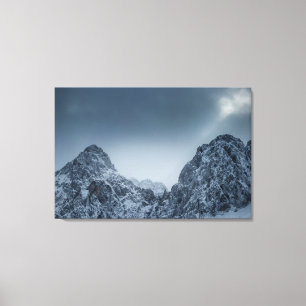 Sonnenlicht und dunkle Wolken über schneebedeckten Leinwanddruck