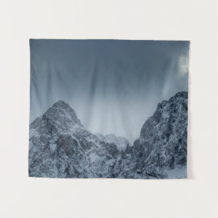 Sonnenlicht und dunkle Wolken über schneebedeckten Wandteppich
