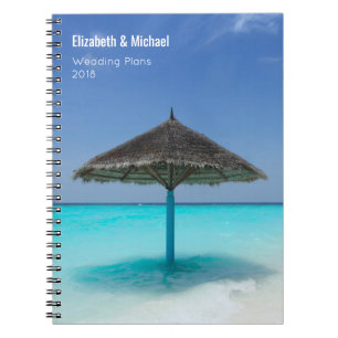 Sonnenschirm aus Strohdach auf Hochzeitsplänen von Notizblock