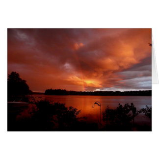 Sonnenuntergang mit Regenbogen am See