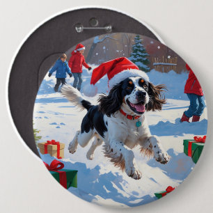 Springer Spaniel läuft durch Schnee mit Weihnachts Button