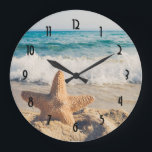 Starfish auf einem Sandy Beach Foto Große Wanduhr<br><div class="desc">Eine Uhr mit einem landschaftlichen Foto. Ein großes Set aus Seestern direkt am Sandstrand. Ein schönes blaues Meer mit weißen Wellen im Hintergrund.</div>