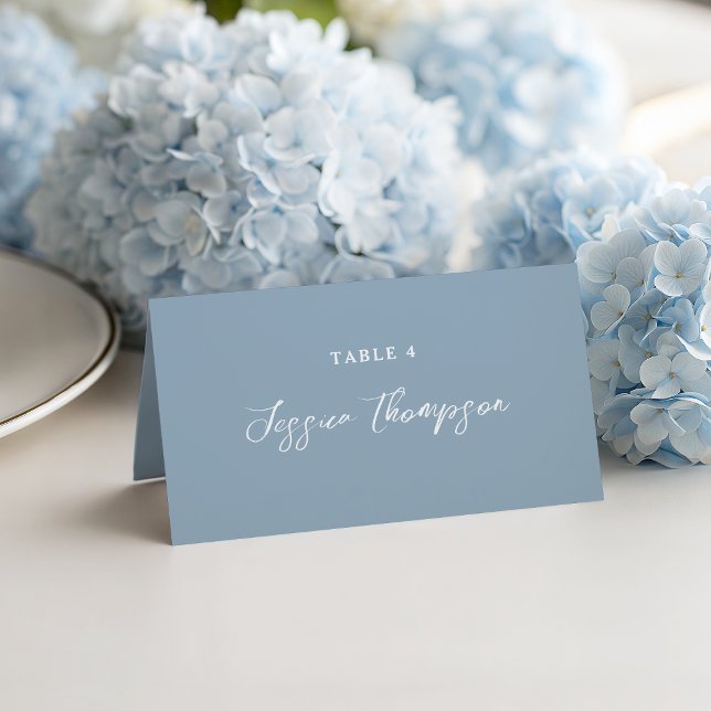 Staubblaues einfaches Skript Elegante Hochzeit Platzkarte (Elegant and simple typography on a beautiful dusty blue background)