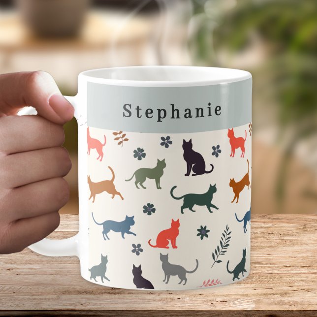Stilvolle Katzenmuster Personalisiert Kaffeetasse (A personalized coffee mug, with a pattern of cat silhouettes in warm and neutral colors)