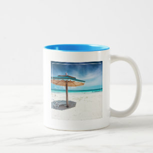 Strand-Stuhl und silberner Sand-Strand des Zweifarbige Tasse