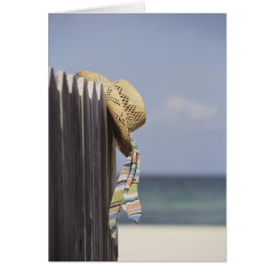 Strohhut auf Zaun am Strand