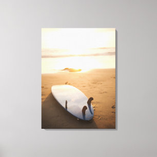 Surfbrett am Strand bei Sonnenuntergang Leinwanddruck