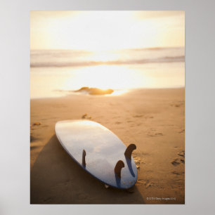 Surfbrett am Strand bei Sonnenuntergang Poster