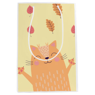 Süße orangefarbene Katze spielt im Herbstlaub Mittlere Geschenktüte