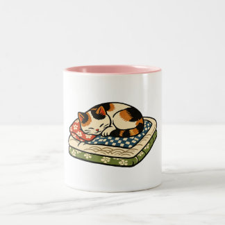 Süße schlafende Dreifarbenkatze auf traditionellem Zweifarbige Tasse