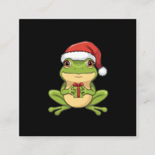 Süßer Weihnachtsfrosch mit Santa-Hut hält Geschenk Begleitkarte