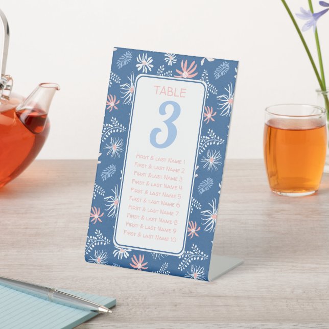 Tabelle mit dunkelblauen und weißen Blumenbestuhlu Sockelschild (In SItu)