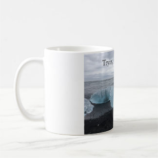 Tasse mit Eis am schwarzen Strand 
