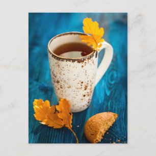Tasse Tee und Herbstlaub auf blauem Holz Postkarte
