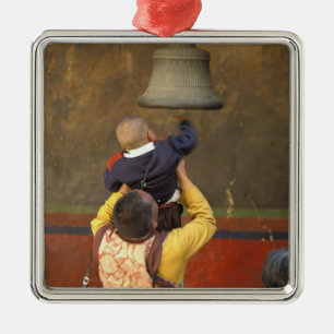 Tibetischer buddhistischer Mönch hebt einen Jungen Silbernes Ornament