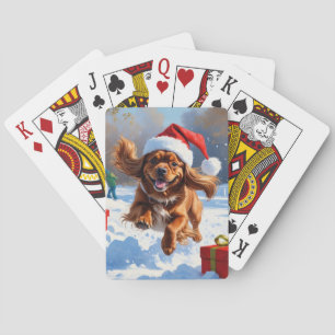 Tibetischer Spaniel läuft im Schnee mit Weihnachts Spielkarten