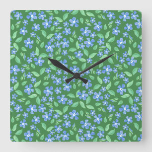 Tollpatschige hellblaue Immergrünblumen auf grünem Quadratische Wanduhr